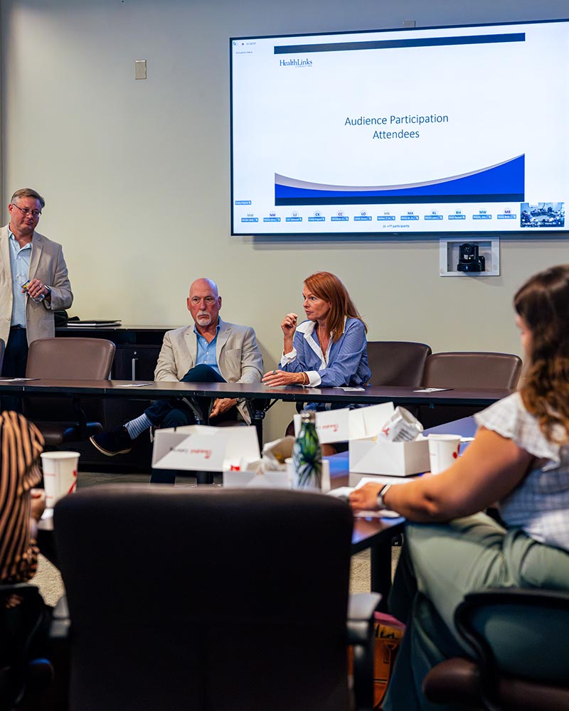Two panelists seated at the conference table answering a question while attendees listen.